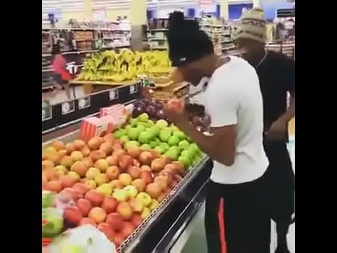 two males taste apples and place them back in supermarket to ensure product quality