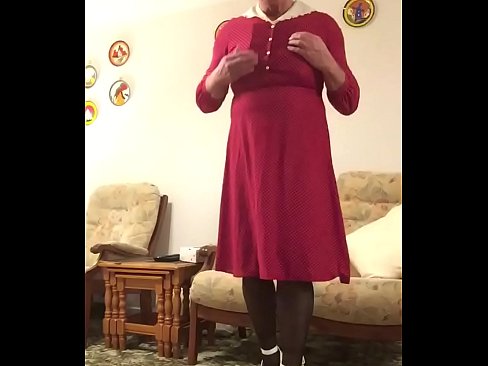 Johanna poses in red dress and white heels in lounge. Using Rimba Electro Stim attached to cock.