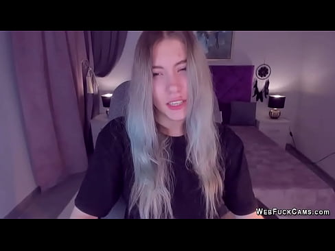 Long haired blonde amateur Ukrainain teen SimaDark in black tshirt sitting in chair in front of her webcam and posing and chatting with fans