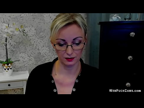 Sexy blonde amateur German MILF in glasses dressed in black blouse with a big cleavage poses and chats with fans on her homemade live webcam show