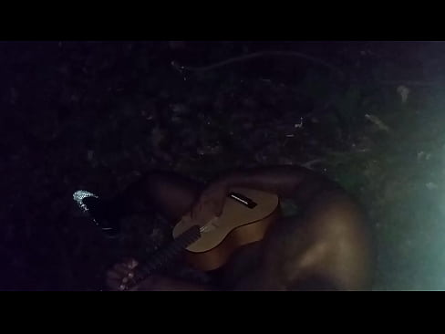 Singing while playing guitar outside at nighttime