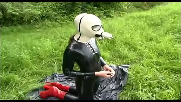 Fetish masked slave dressed in latex wandering in the countryside