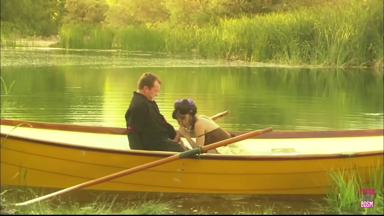 A slender young woman engages in sexual intercourse with a man's large penis while aboard a boat on a lake