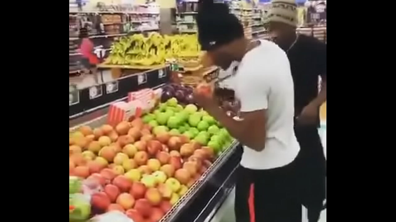 two males taste apples and place them back in supermarket to ensure product quality