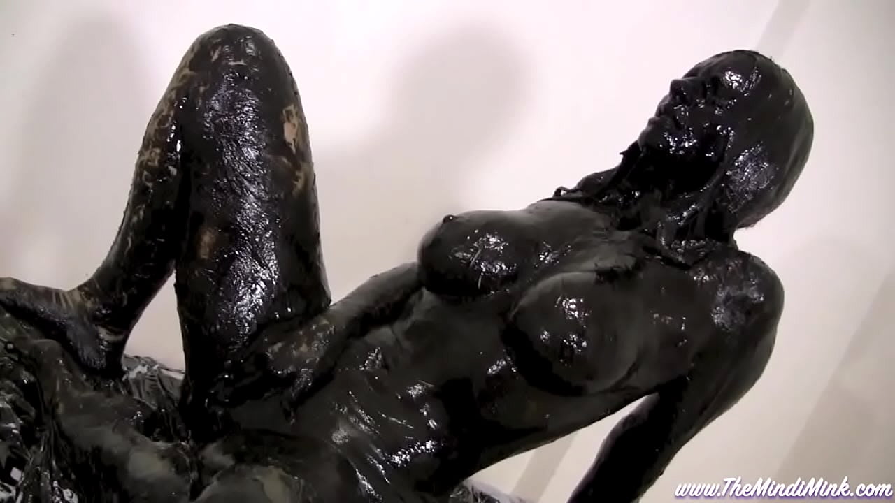 Mindy mink covered in black grease in front of mirror solo