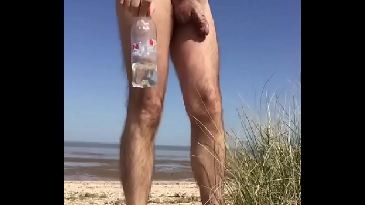 Naked man drinks at the nudist beach