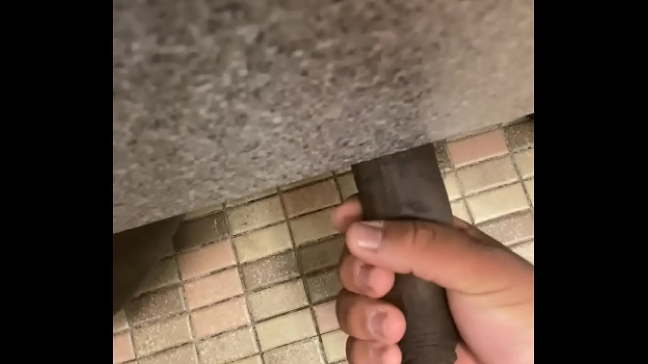 Giving a handjob to uncut BBC under a stall in a public bathroom