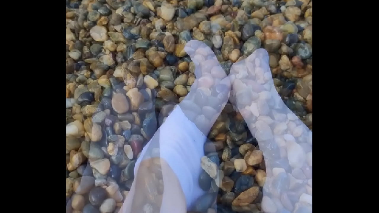 Playing with my feet in white socks with pebbles on the beach