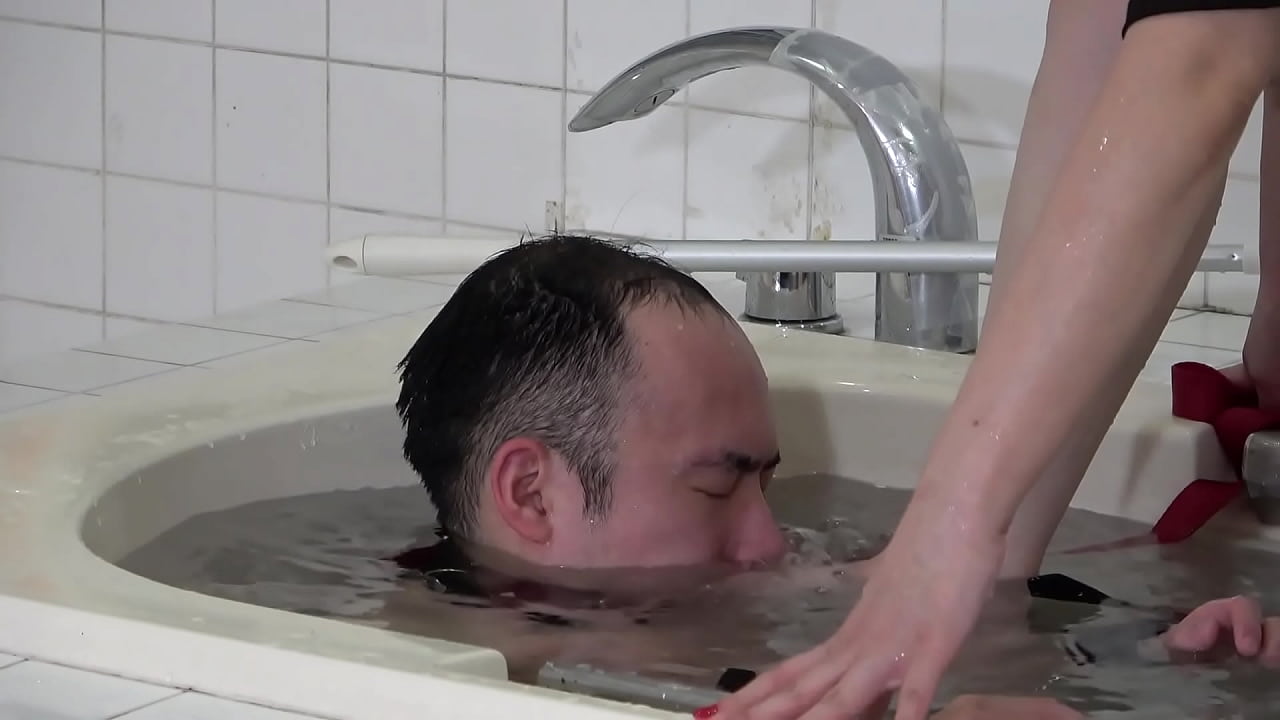 Japenese girl submerges a man into the bathtub with a facesitting