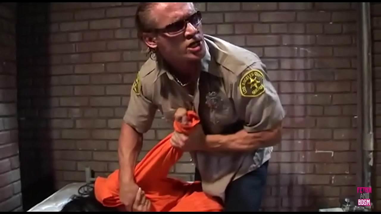 A female prisoner with brown hair receives sexual attention from a guard, as another convict engages in self-stimulation.