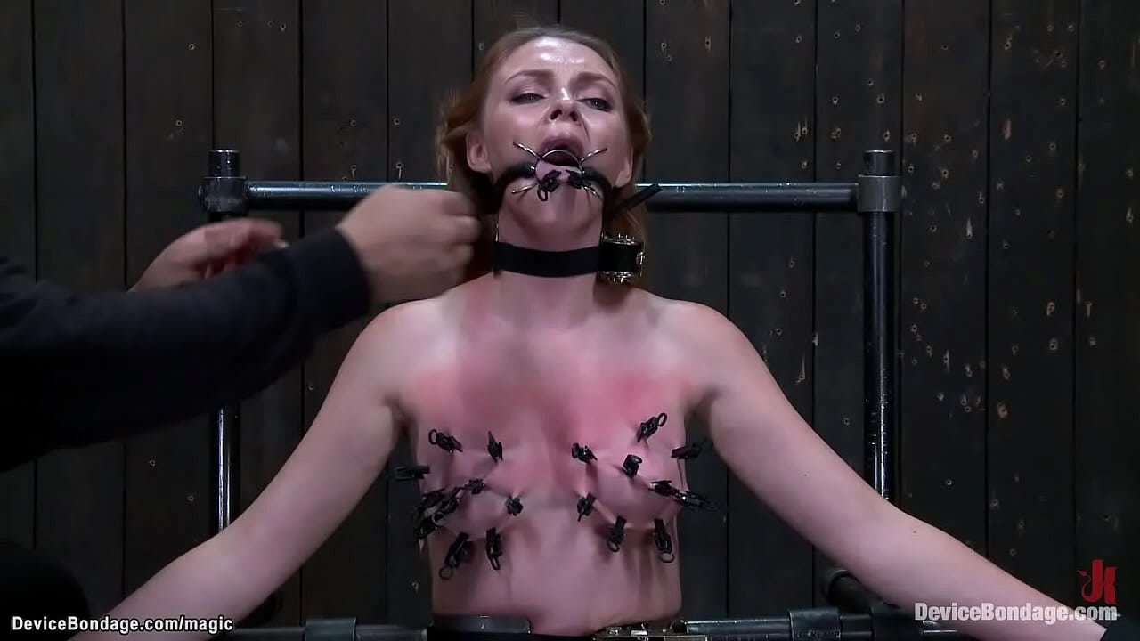 Gagged redhead slave Marie McCray is straddled on Sybian on knees with body bound in metal device gets tongue and skin clamped by master Orlando