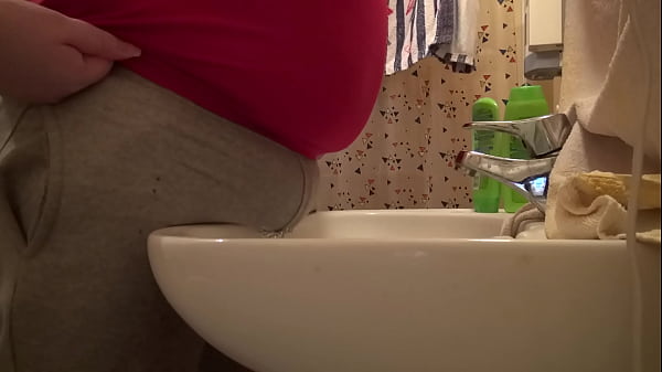 tisser gjennom gr&aring; bukse over vasken p&aring; badet