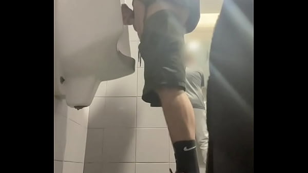 2 boys in sneakers having fun at public toilets' urinal