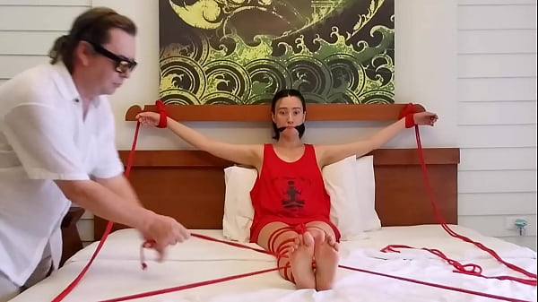 The girl was tied to the bed with red ropes and gagged with a black cloth
