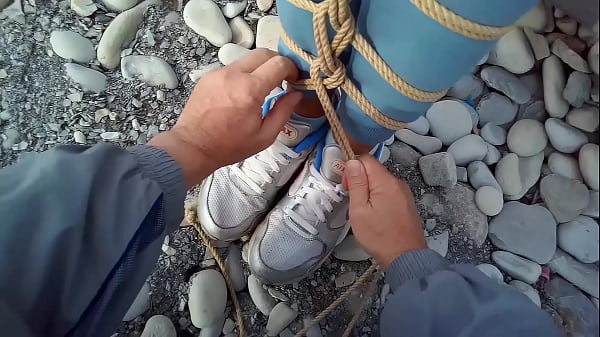 A girl was tied up with jute ropes next to the sea. POV