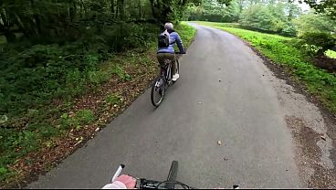 A woman in the woods riding a bike, I ask her to watch my bike so it doesn't get stolen. When I go to urinate, I call her over and she helps me masturbate and gives me a blowjob under the green nature of the public forest  