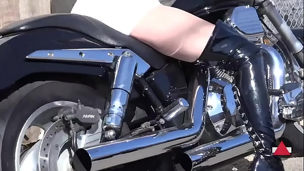 Shiny boot girl clicks on street bike