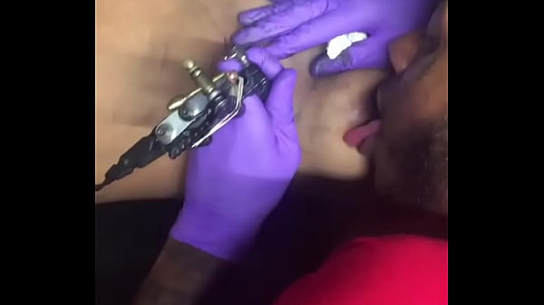 Horny tattoo artist multi-tasking sucking client's nipples