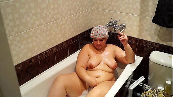 A mature BBW lay down in the bath, lit a cigarette and smokes relish.  