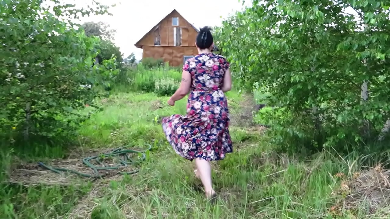 Milf without underwear under her dress outdoors in the yard. She picks a cucumber from the garden and fucks her cunt with it.