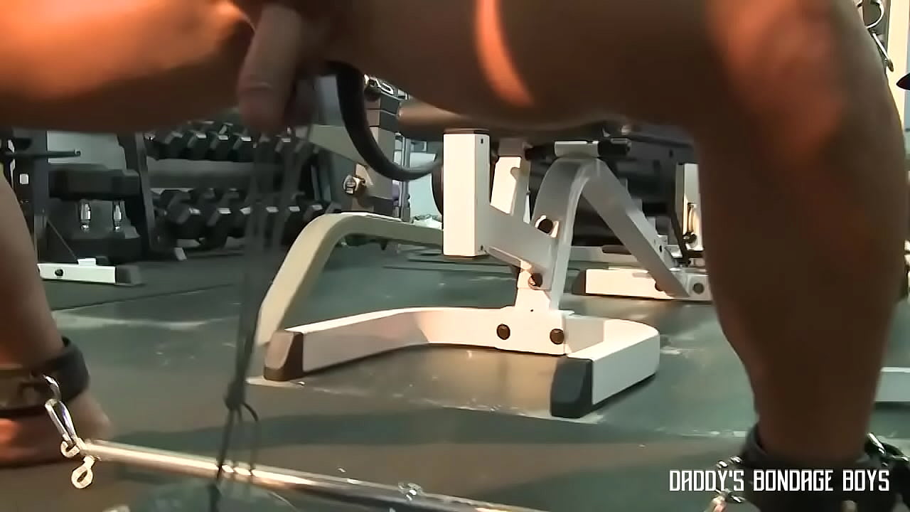 Muscular guy does squats with weights tied onto his nuts