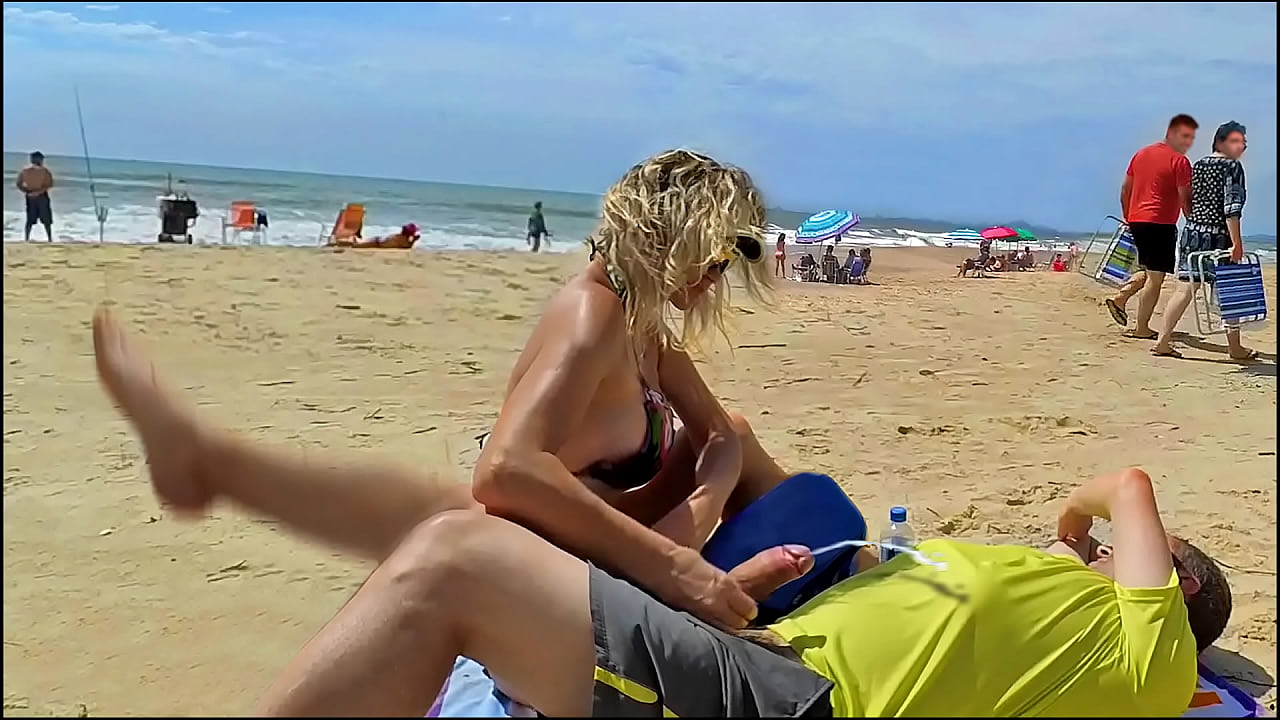 Milf makes stranger ejaculate with skillful handjob right on the beach