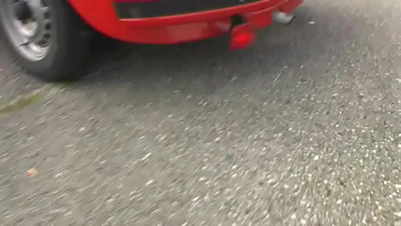 Bimba siting barefoot in her Volkswagen car revving the engine