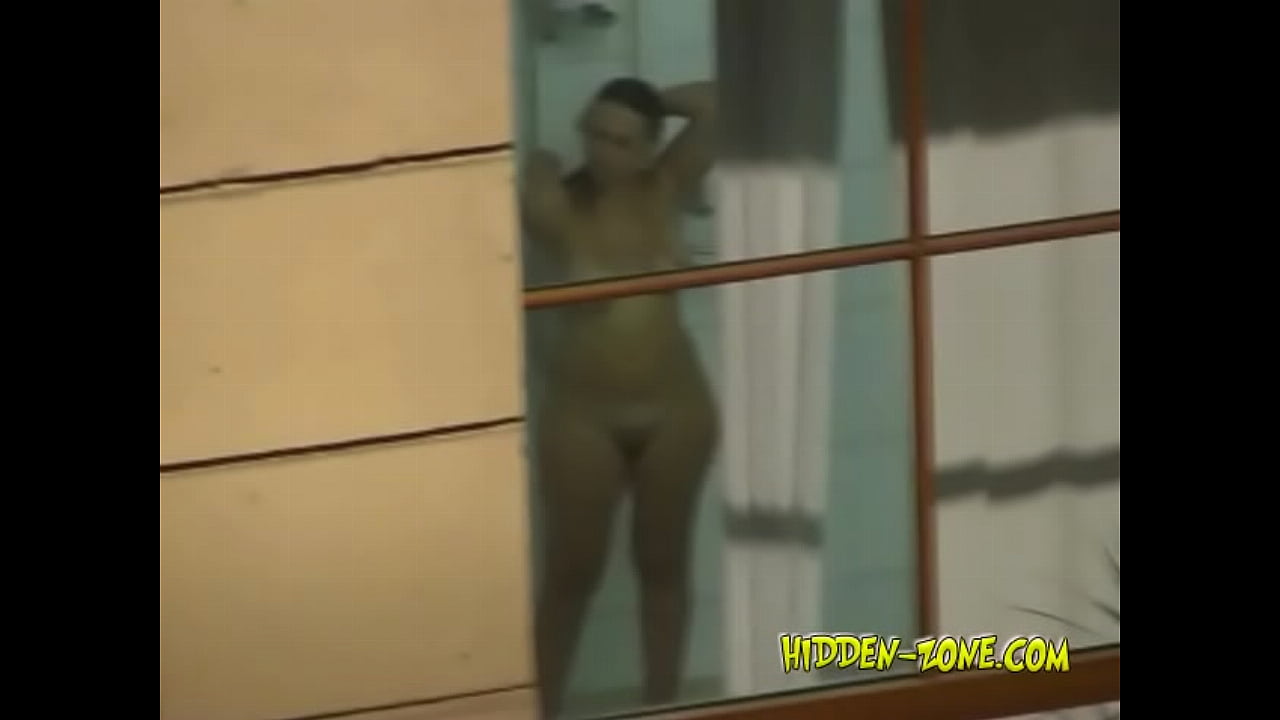 A girl washes in the shower, and we see her through the window