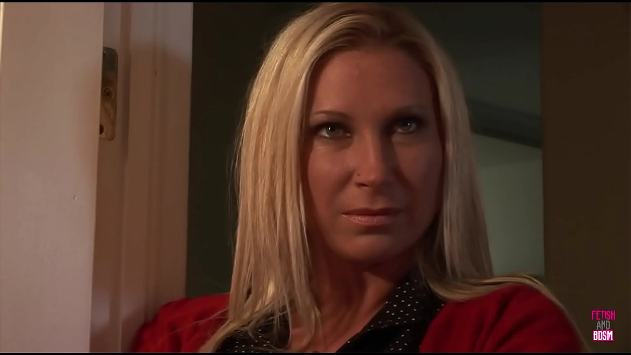 A man exercises control over a well-endowed blonde woman who is restrained in the restroom