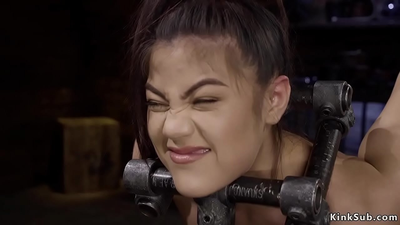 Brunette slave Kendra Spade with head locked and slightly bent forward in metal device bondage gets hot ass spanked then in other positions toyed