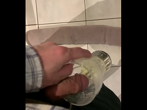 Man pisses in a glass. Cat watches briefly.