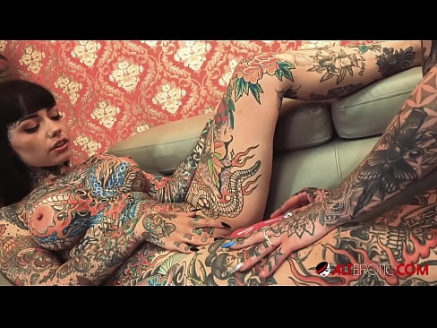 Two beautiful women with tattoos fuck each other with a strap on