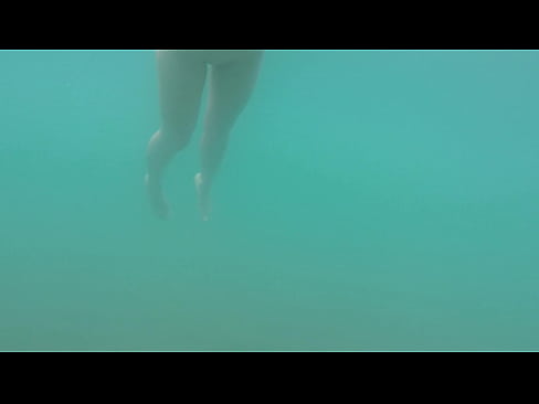Nudist beach: Skinny dipped girl swimming in the sea.