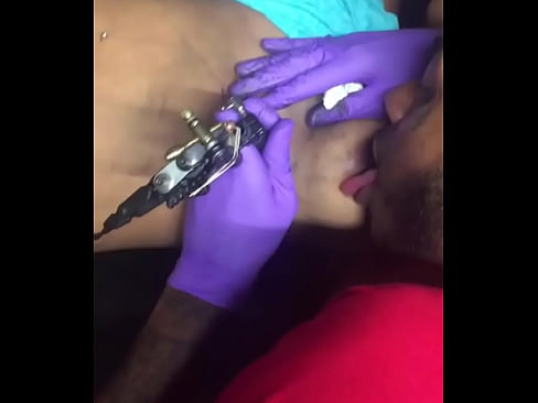 Horny tattoo artist multi-tasking sucking client's nipples