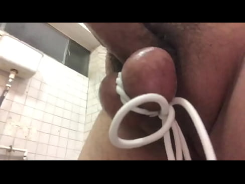 Tied cock jerking off in public toilet